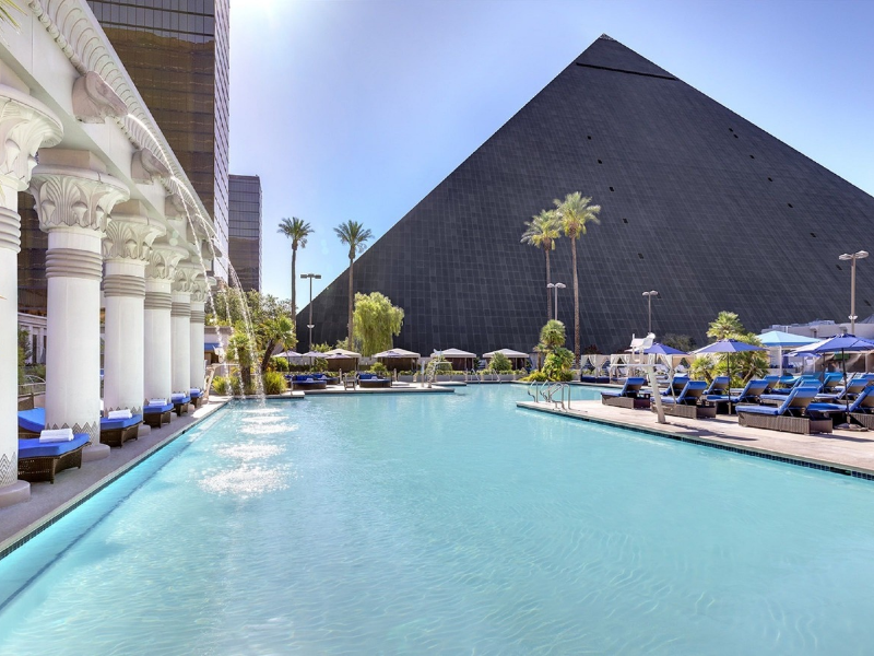 a pool with a pyramid in the background with Luxor Las Vegas in the background