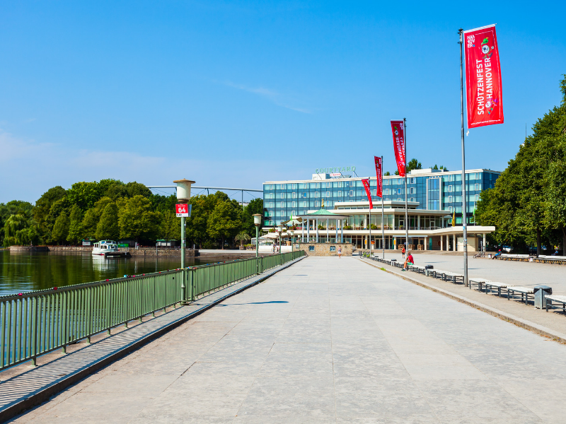 a walkway with red flags and a building in the background